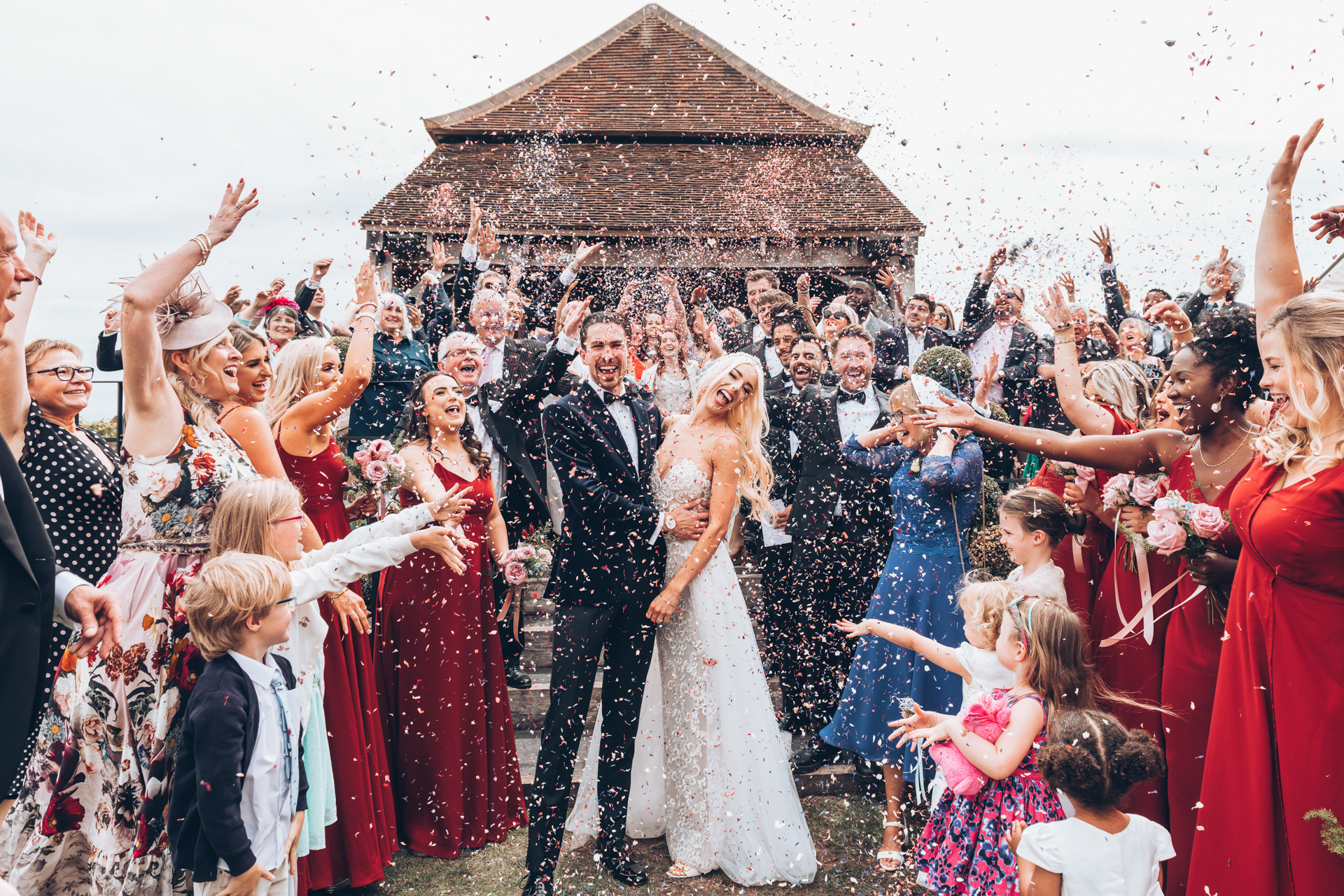 A bride and groom have confetti thrown over them at the Farmhouse at redcoats