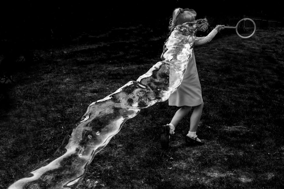 A young wedding guest plays with a bubble